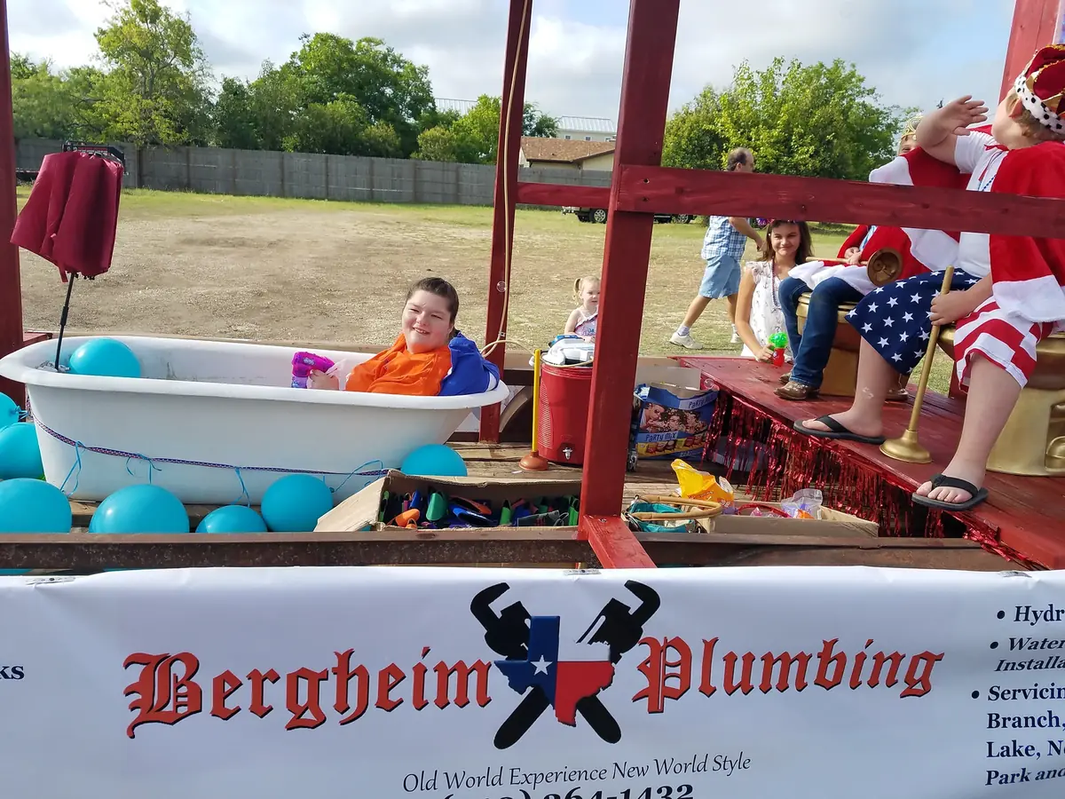 Child riding in a clawfoot tub on the Bergheim Plumbing parade float at Berges Fest