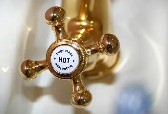 Ornate brass cross handle tap marked HOT in a period bathroom