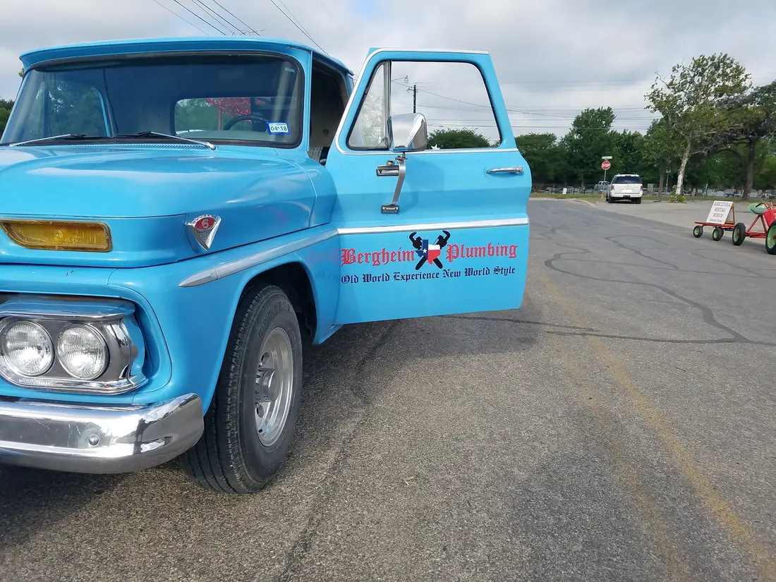 Light blue vintage Chevrolet pickup lettered for Bergheim Plumbing on a country road
