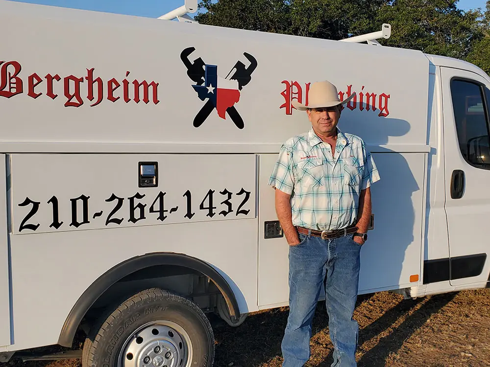 Bergheim Plumbing van with 210-264-1432 lettered large beside a man in a cowboy hat