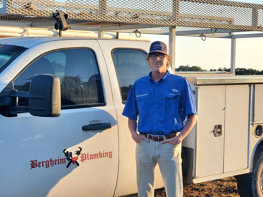 Young technician in a blue shirt standing at the door of the white service truck