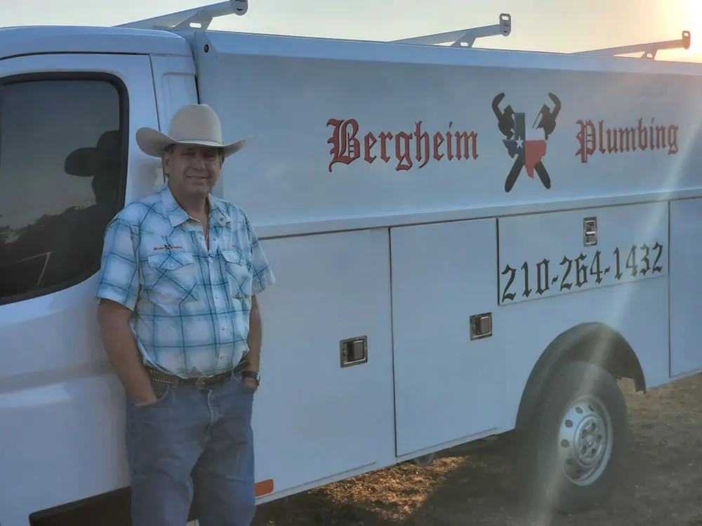 Man in a straw cowboy hat and plaid shirt standing beside the Bergheim service van
