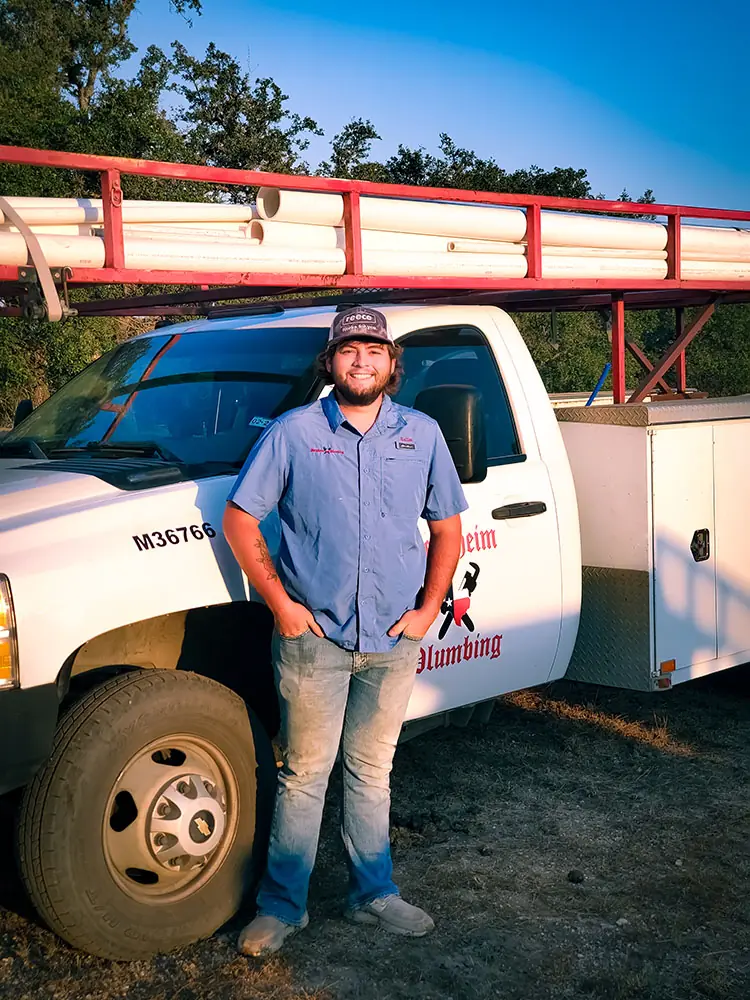 Technician in a blue company shirt standing beside a truck with a red ladder rack