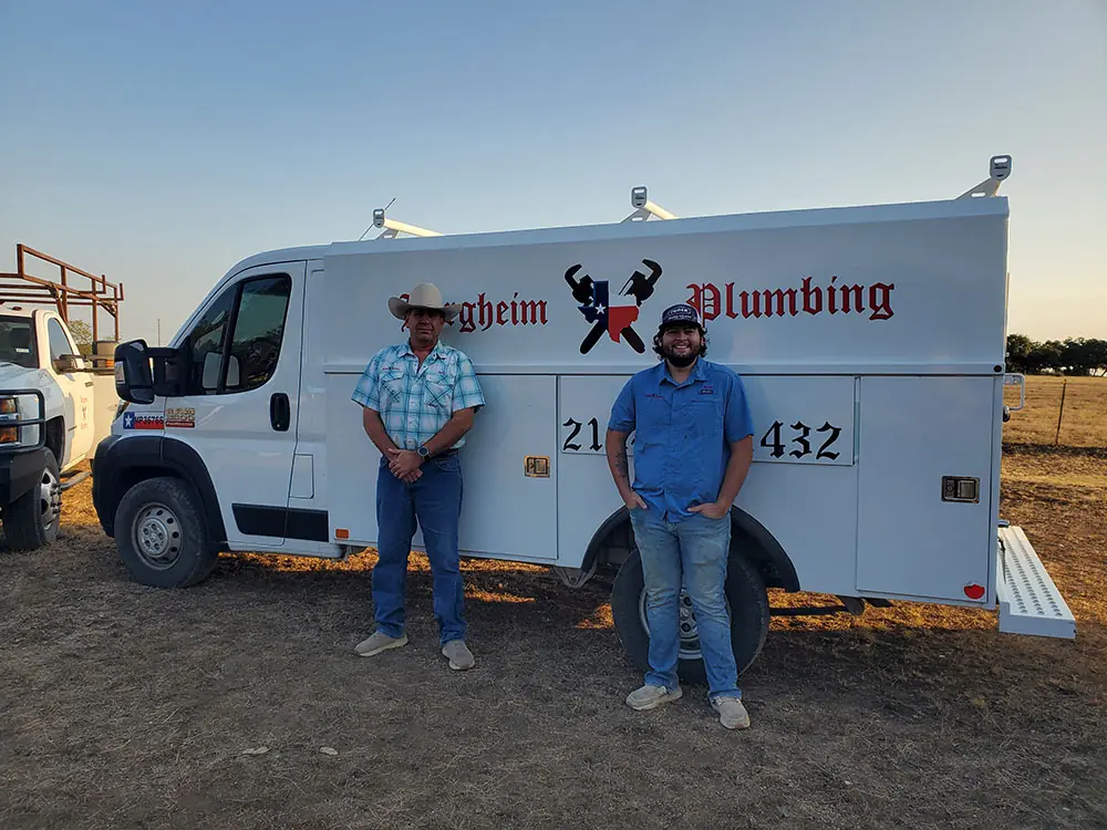 Two Bergheim Plumbing staff standing by the service van as the light goes