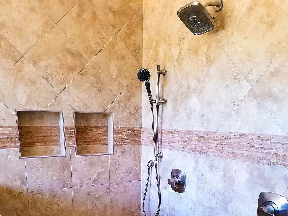 Travertine shower with two recessed niches, handheld shower and valve trim fitted
