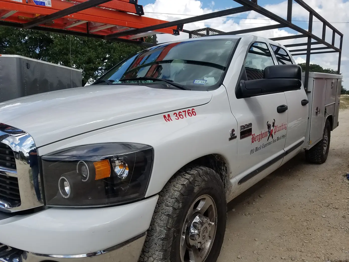 White Dodge Ram service truck with a utility bed lettered for Bergheim Plumbing