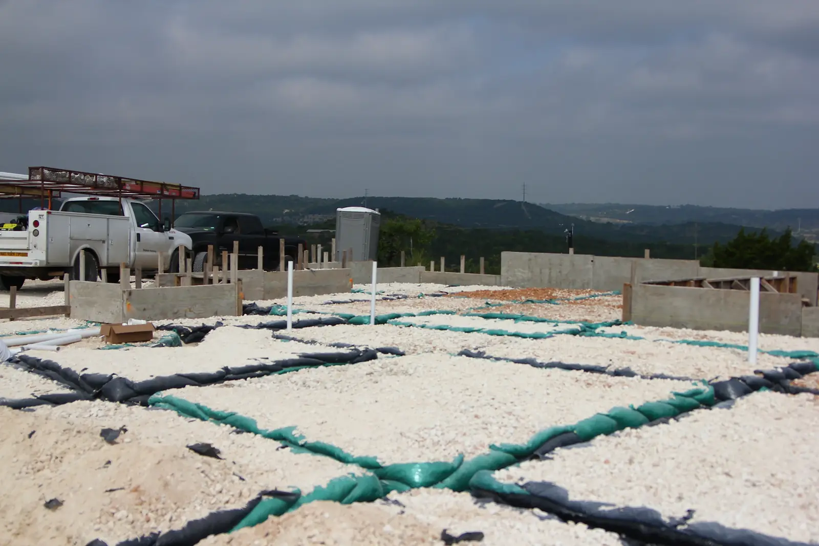 Under-slab plumbing lines on a gravel pad with a Bergheim service truck behind